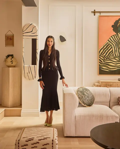 Faten M standing in a finished living room she designed