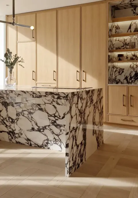 Kitchen with oak cabinetry and a Calacatta Viola marble waterfall island