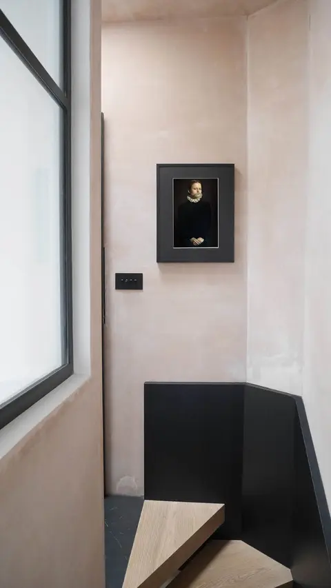 Polished plaster stairwell with a black painted stair and a framed portrait