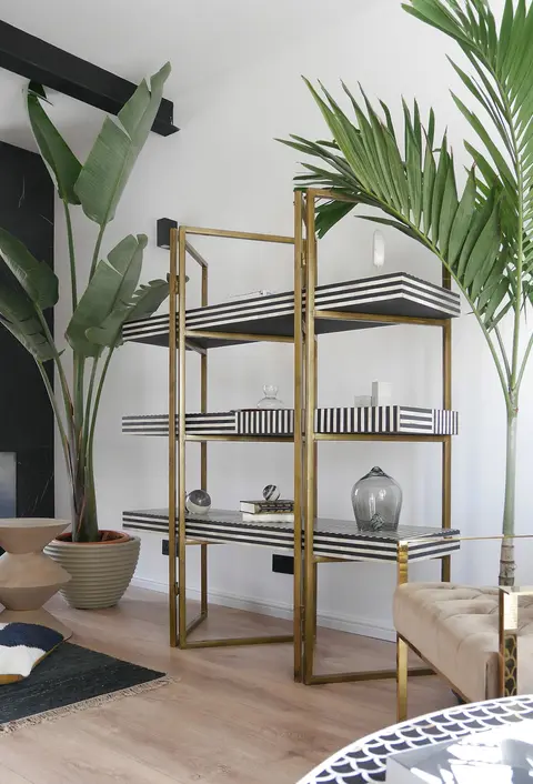 Saul shelf styled with books and objects next to tall plants
