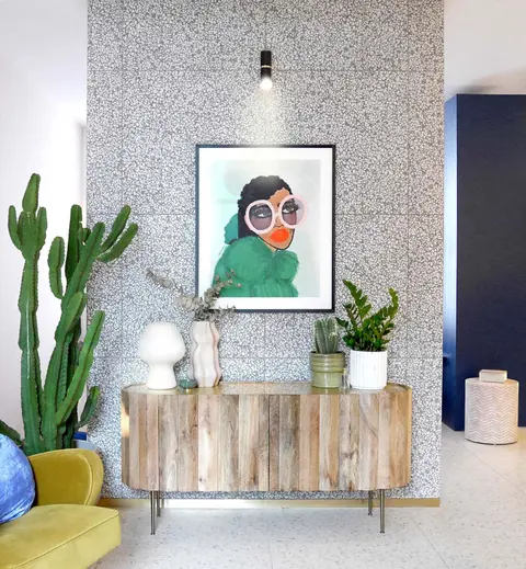 Hallway with terrazzo walls, a reclaimed-wood sideboard, a cactus and a bold portrait print
